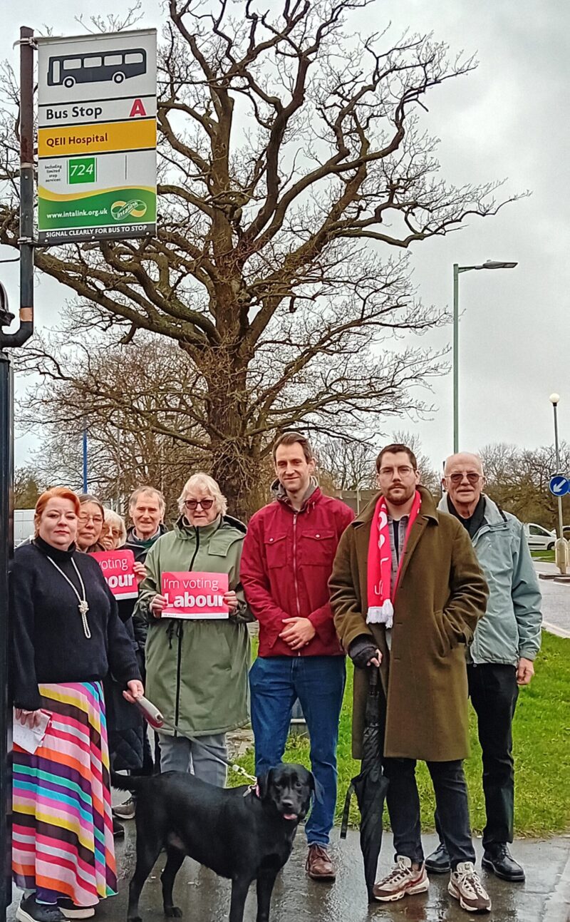 Labour Party members stand outside the QEII bus stop.